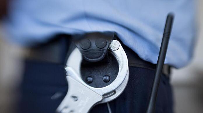 Handschellen hängen am Gürtel eines Justizbeamten.