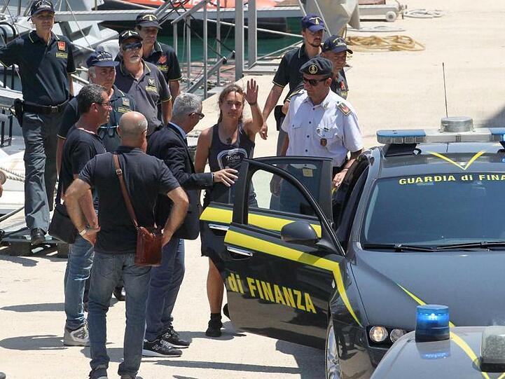 Carola Rackete (M.), deutsche Kapitänin der "Sea-Watch 3", winkt, als sie am 1. Juli nach ihrer Ankunft im Hafen von Porto Empedocle in ein Polizeiauto steigt.