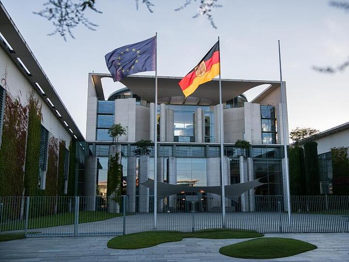 Die deutsche und die EU-Flagge vor dem Kanzleramt in Berlin.