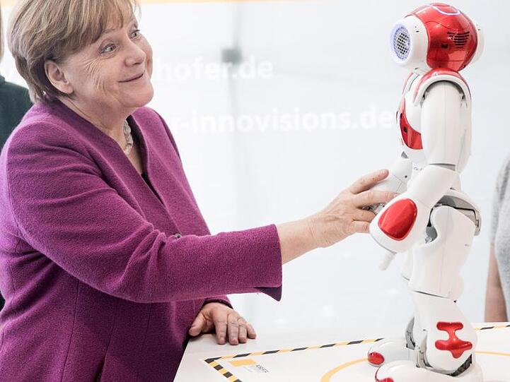 Bundeskanzlerin Angela Merkel (CDU) macht Bekanntschaft mit dem Roboter Nao. Foto: Jörg Carstensen/Archiv