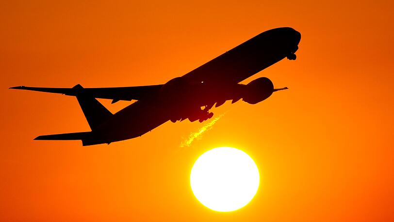 Ein Flugzeug startet vom Frankfurter Flughafen in den Sonnenuntergang. (Symbolbild)