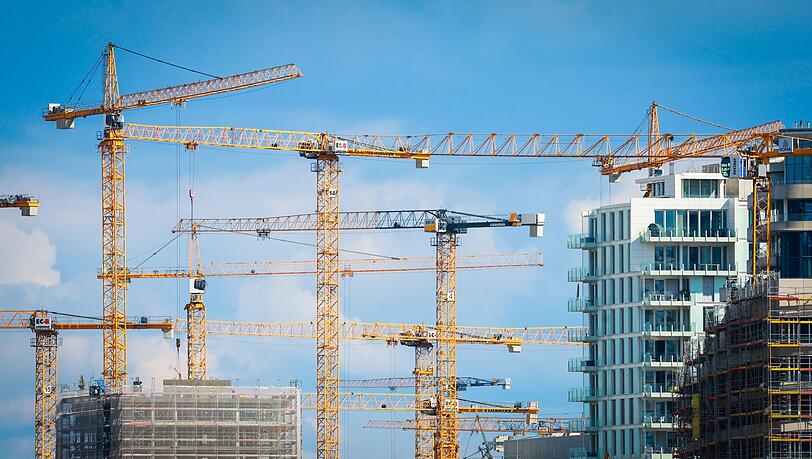 Baukräne stehen auf einer Baustelle in einer Innenstadt.