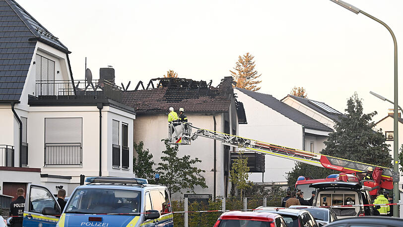 Einsatzkräfte der Feuerwehr und der Polizei stehen nach Brand vor dem Wohnhaus im Stadtteil Lerchenau.