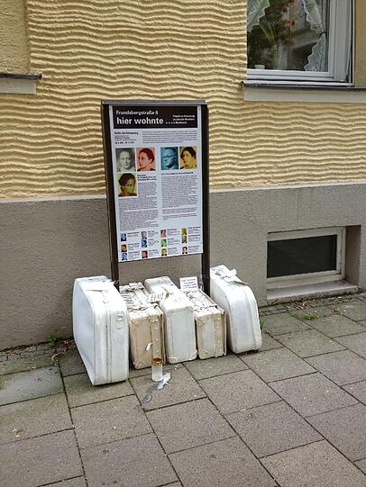 Die Schautafel zeigt Fotos der jüdischen Nachbarn, die einst im Viertel lebten.
