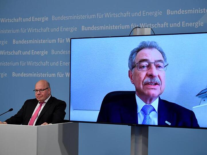Bundeswirtschaftsminister Peter Altmaier (l) sitzt neben einer Leinwand, auf der BDI-Präsident Dieter Kempf zu sehen ist.
