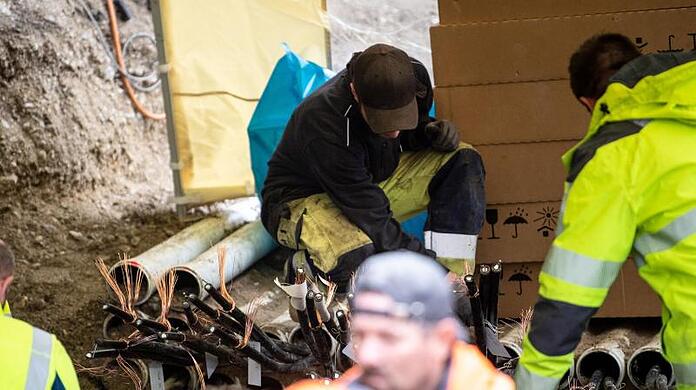 Arbeiter reparieren an einer Baustelle die Leitungen, die durch den mutmaßlichen Brandanschlag zerstört wurden.