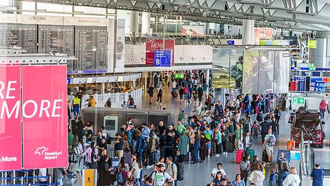 Reisende stehen am Frankfurter Flughafen beim Einchecken in einer langen Schlange.