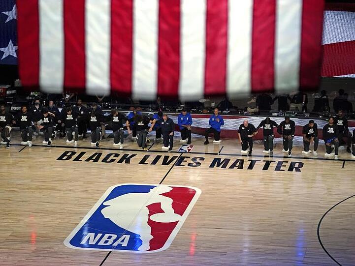 Die Spieler von den Milwaukee Bucks und den Orlando Magic knien vor dem Spiel nieder.