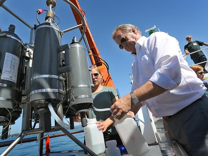 Franz Untersteller (Die Grünen) nimmt frisch geschöpftes Wasser aus einem Rosettenwasserschöpfer. Foto: Karl-Josef Hildenbrand