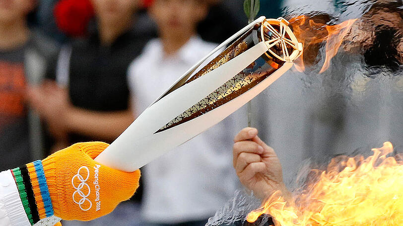 Der griechische Skirennfahrer Ioannis Proios entzündet in Athen die Olympische Fackel während der Übergabezeremonie der Olympischen Flamme im Panathinaikon Stadion.
