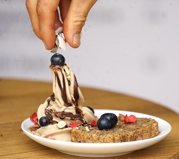 Das Bananeneis mit einem Stück Bananenbrot, Kokossplittern und Beeren.