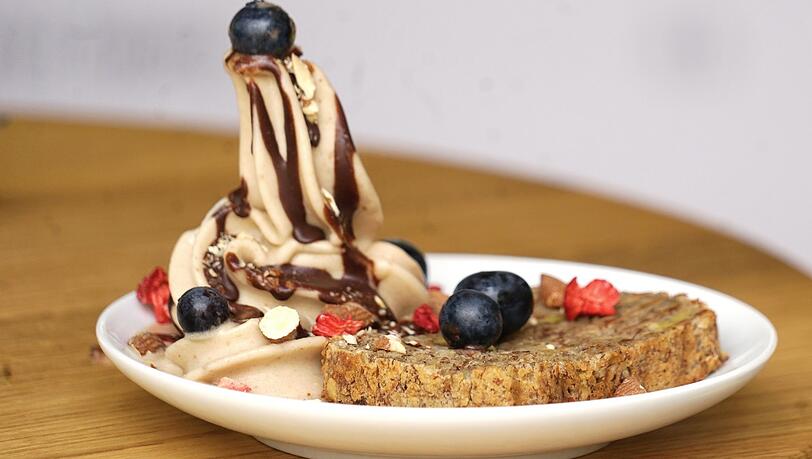 Das Bananeneis mit einem Stück Bananenbrot, Kokossplittern und Beeren.