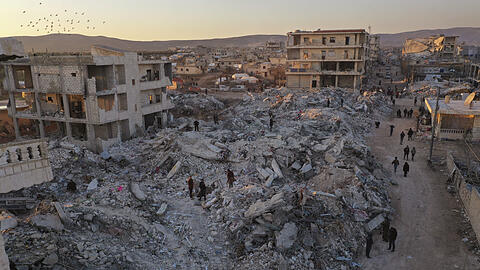 Jinderis in Syrien: Menschen gehen an eingestürzten Gebäuden vorbei. Die türkisch-syrische Grenzregion ist von dem Erdbeben schwer getroffen.