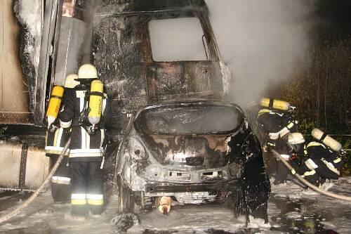 Der Corsa und das Führerhaus sind ausgebrannt, während Feuerwehrleute noch mit Löschschaum hantieren.