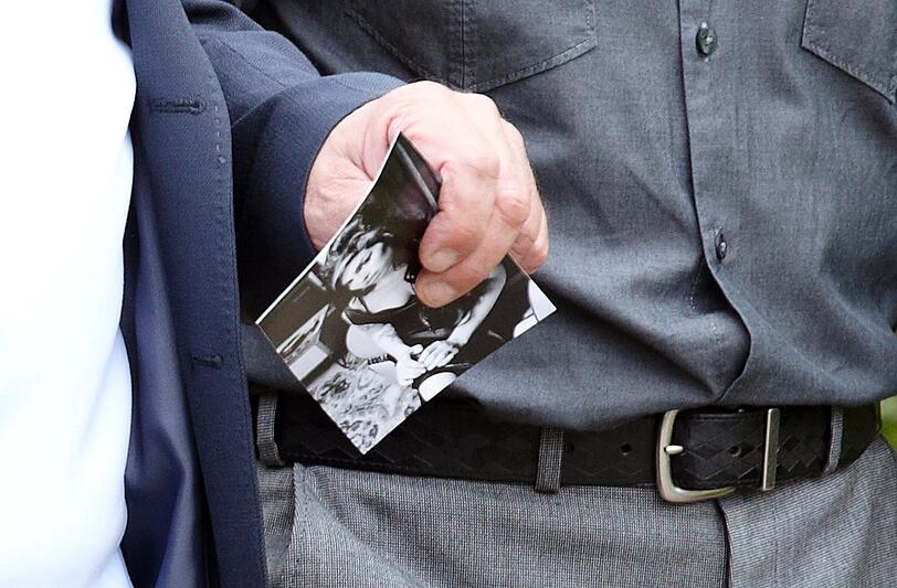 Ein Trauergast hält ein Bild von Amy in der Hand.