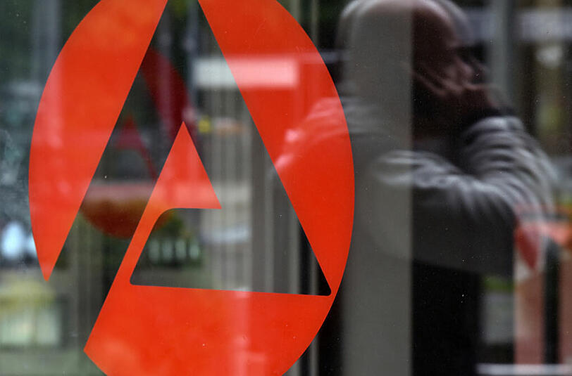 Ein Mann spiegelt sich in München im verglasten Eingangsbereich der Agentur für Arbeit.