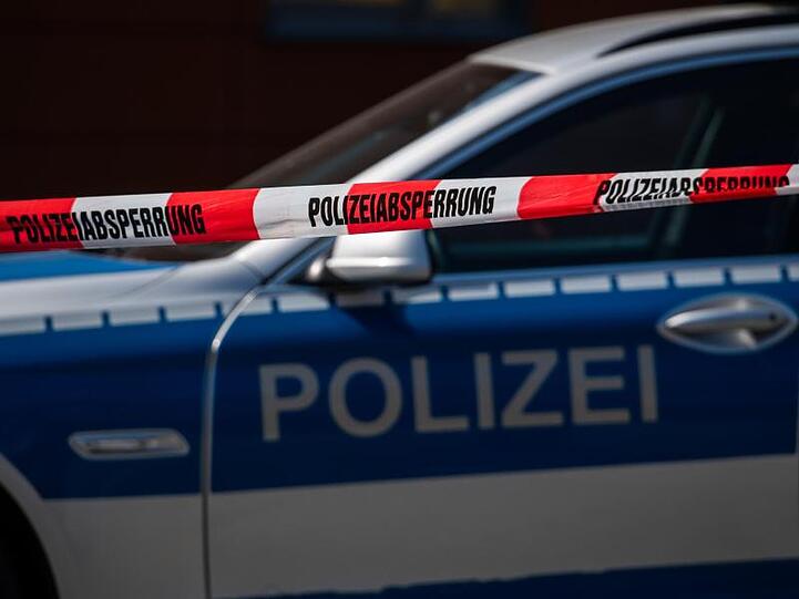Ein Polizeiauto steht hinter einer Polizeiabsperrung. Foto: Robert Michael/dpa-Zentralbild/dpa/Archivbild