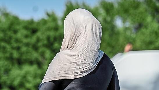 Eine Frau in einem Burkini mit Kopftuch im Freibad.