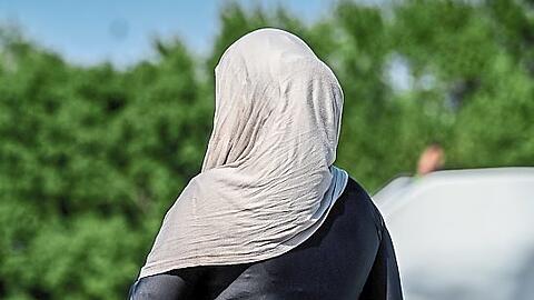 Eine Frau in einem Burkini mit Kopftuch im Freibad.