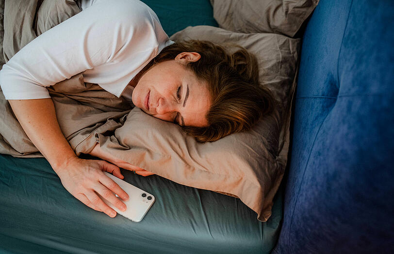 Eine Frau liegt im Bett und hat noch ihr Handy in der Hand. Zu viel Zeit am Smartphone ist laut Dietrich Grönemeyer ein Faktor, der sich auf den Schlaf auswirkt. Eine Frau liegt im Bett und hat noch ihr Handy in der Hand. Zu viel Zeit am Smartphone ist laut Dietrich Grönemeyer ein Faktor, der sich auf den Schlaf auswirkt.