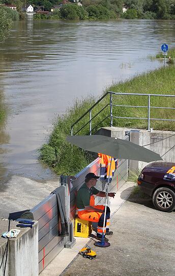 Ein Helfer sitzt am Mittwoch in Deggendorf vor einer Hochwassersperre, ...