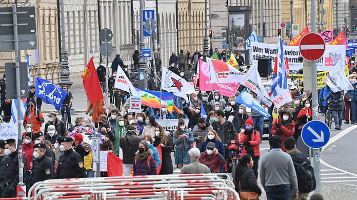 Teilnehmer gehen beim Ostermarsch mit Bannern, Fahnen und Plakaten durch die Münchner Innenstadt.
