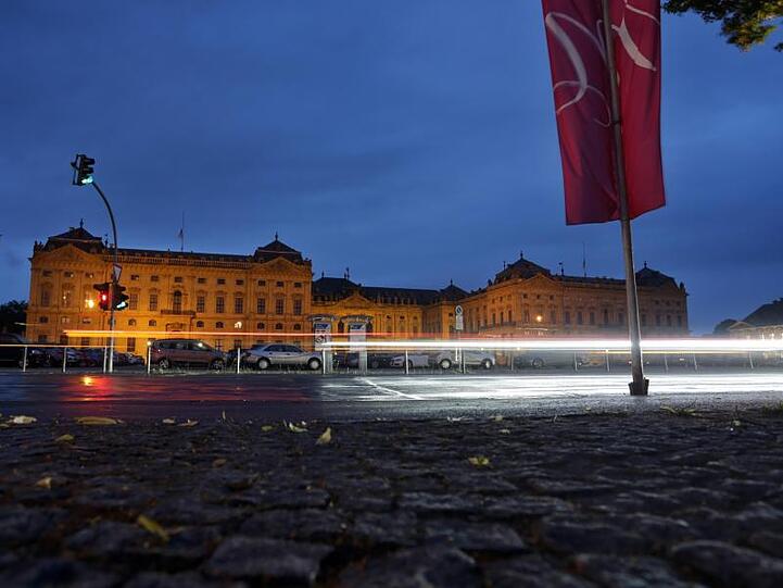 Die Fahne des Mozartfestes und Lichter von vorbeifahrenden Autos sind vor der Residenz in Würzburg zu sehen. Foto: K.-J. Hildenbrand/Archiv
