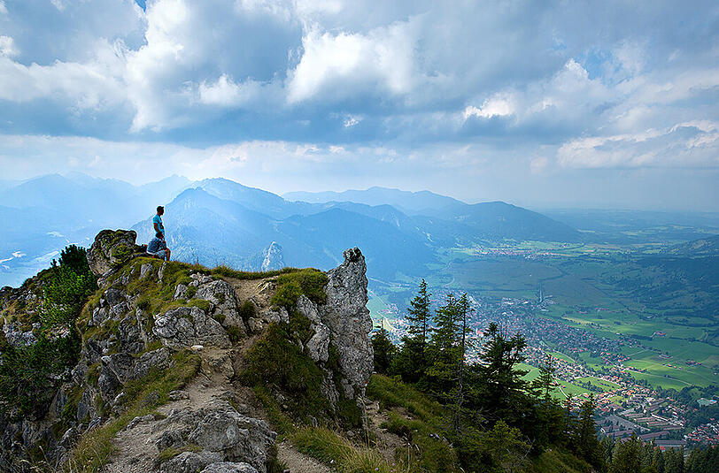 Natur pur in Bayern. Hier stehen zwei Männer auf einem Berg mit Blick auf das Örtchen Oberammergau.