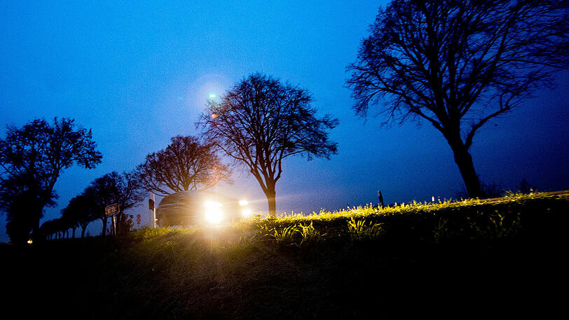 Ein Mann liegt nachts auf einer Waldstraße auf dem Boden - und wird von einem Fahrzeug erfasst.