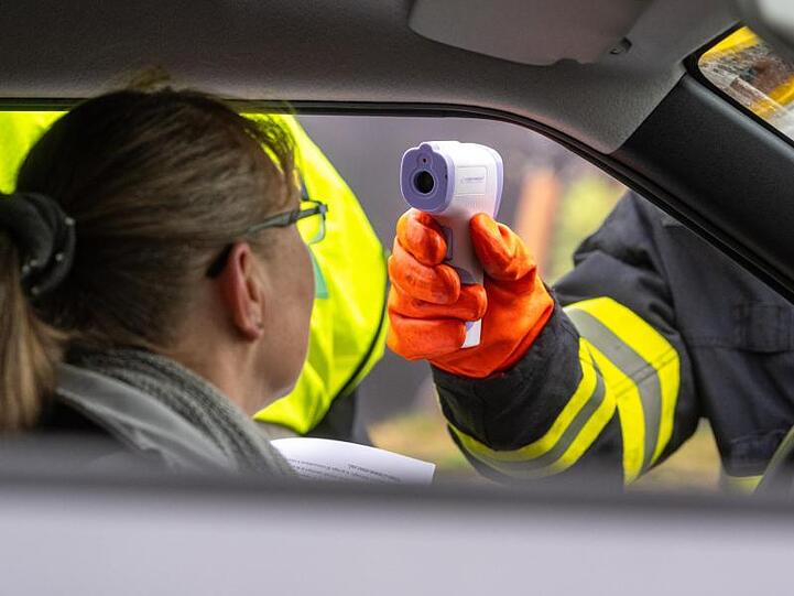 Ein Feuerwehrmann aus Tschechien misst and der Grenze die Temperatur von einer Einreisenden. Foto: Armin Weigel/dpa