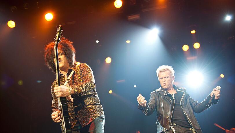 Steve Stevens, Gitarrist und Begleiter seit den ersten Tagen, und Billy Idol, der selbst auf der schwülsten Bühne sein Konzert in vollem Ornat beginnt. Steve Stevens, Gitarrist und Begleiter seit den ersten Tagen, und Billy Idol, der selbst auf der schwülsten Bühne sein Konzert in vollem Ornat beginnt.