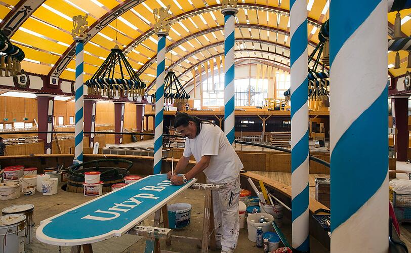 Kunstmaler Rudi Weger arbeitet fuer das Oktoberfest 2012 im Loewenbraeu-Festzelt am Schild einer Urtyp-Box .