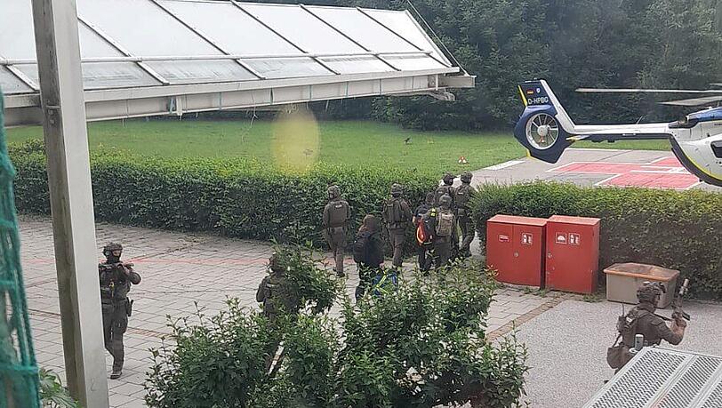 Beamte eines Spezialeinsatzkommandos bringen den 49-J&auml;hrigen in Fu&szlig;fesseln zu einem Polizeihubschrauber.