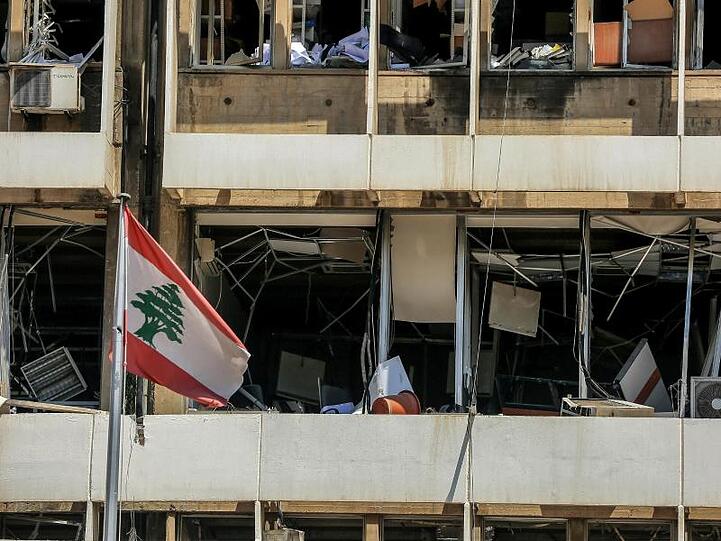 Die libanesische Flagge vor der Fassade eines zerstörten Bürogebäudes in Beirut.