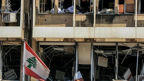 Die libanesische Flagge vor der Fassade eines zerstörten Bürogebäudes in Beirut.