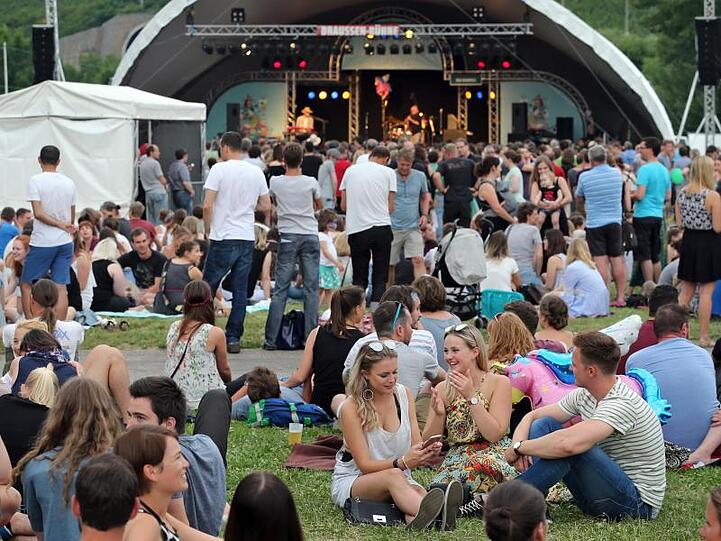 Besucher des Musikfestivals "Umsonst & Draußen" sitzen vor einer Bühne des Festivals. Foto: Karl-Josef Hildenbrand/Archivbild