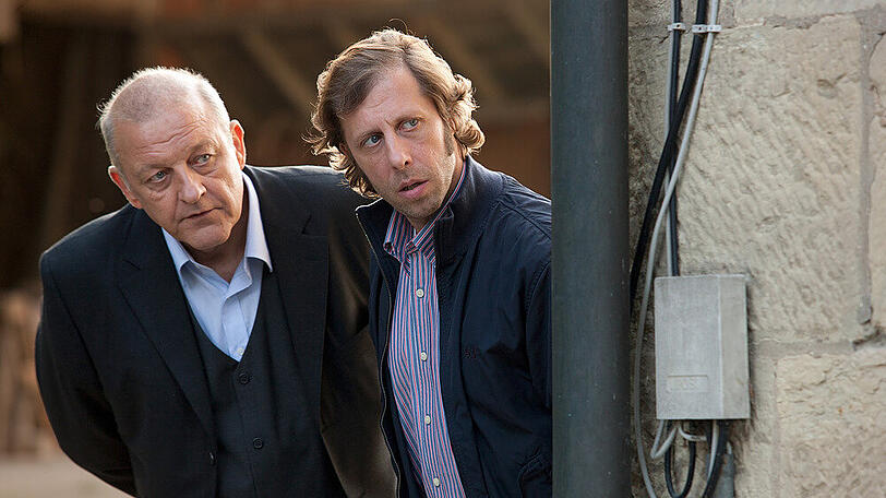 "Wilsberg: Gegen den Strom": Wilsberg (Leonard Lansink, l.) und Ekki (Oliver Korittke, r.) beobachten unauffällig das Geschehen.