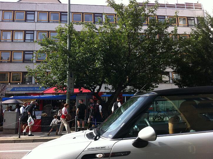 In der Poccistraße stehen Autofahrer im Stau. Daneben feiern Oktoberfestfans, Musik dröhnt aus den Boxen.