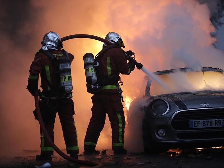 Feuerwehrleute löschen bei einem Protest der "Gelbwesten" in der Nähe der Champs-Élysées ein brennendes Auto.