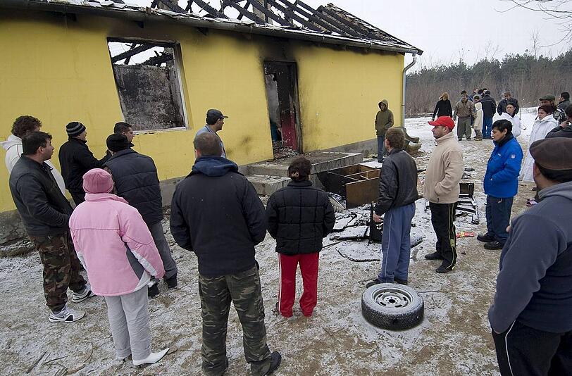 Nachbarn betrachten die Brandruine im ungarischen Dorf Tatarszentgyörgy, wo ein Vater und sein Sohn von Neonazis ermordet worden sind.