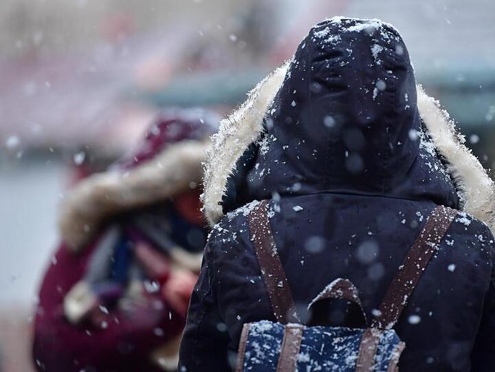 Zwei Personen warten bei Schneewetter. Foto: Hendrik Schmidt/ZB/dpa +++ dpa-Bildfunk +++