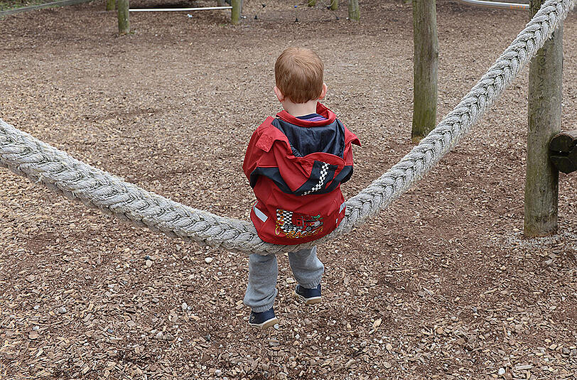 Ein Junge sitzt allein auf einer Schaukel auf einem Abenteuerspielplatz - Symbolfoto