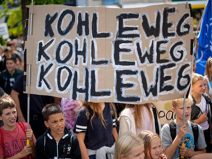 Teilnehmer der Klimademonstration "Fridays for Future" stehen mit Transparenten auf einer Demo. Foto: Monika Skolimowska/dpa-Zentralbild/ZB