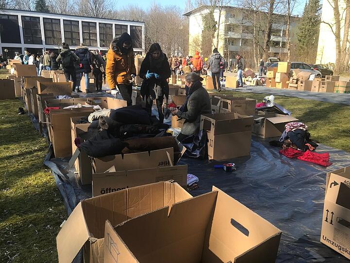 Kleider, Konserven, Schlafsäcke - kistenweise stapeln sich in den ersten Kriegstagen Hilfsgüter auf der Wiese hinter der Kirche.