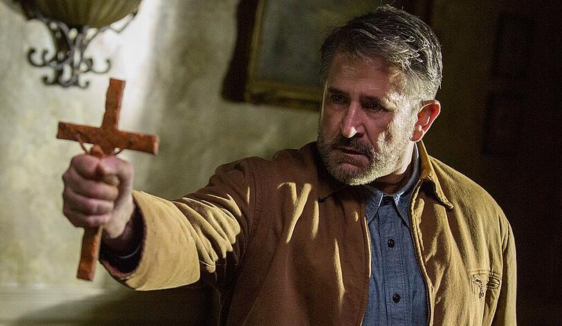 Gastgeber Samuel Mullins (Anthony LaPaglia) versucht der bösen Macht mit dem Kruzifix beizukommen.