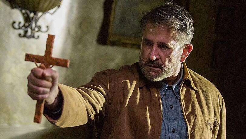 Gastgeber Samuel Mullins (Anthony LaPaglia) versucht der bösen Macht mit dem Kruzifix beizukommen.