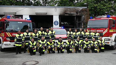 Die Kameradinnen und Kameraden der Freiwilligen Feuerwehr Freimann - im Hintergrund ist die ausgebrannte Fahrzeughalle zu sehen.