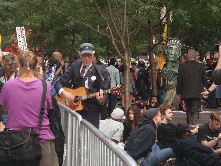 Sitzstreik mitten im New Yorker Finanzdisktrikt. Der Bereich ist zwar abgesperrt, aber jeder kommt problemlos durch die Zugänge rein und raus. Die Polizei schaut zu.