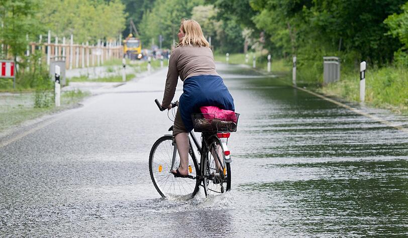 Eine Radlerin kämpft mit den Fluten.