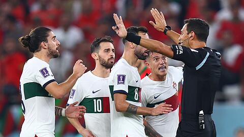 Portugiesische Spieler fordern von Schiedsrichter Facundo Tello einen Elfmeter.
